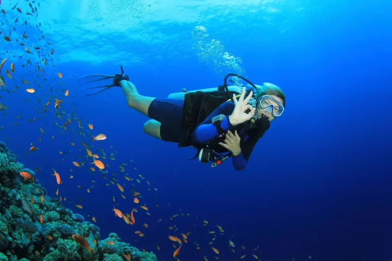 Female scuba diver underwater showing ok signal